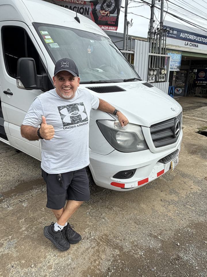 Oscar y un cliente junto a la van, bajo la lluvia