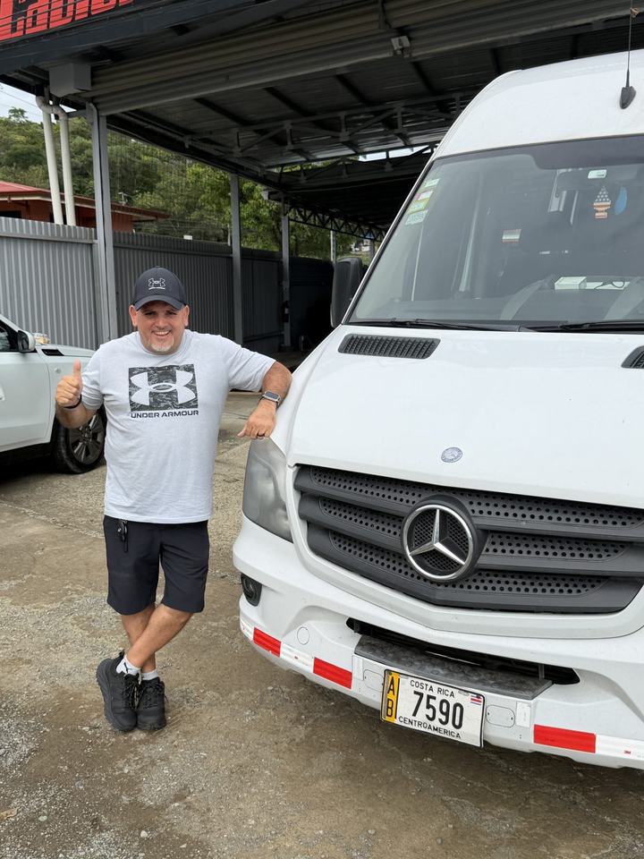Oscar con clientes junto a la van blanca, de noche